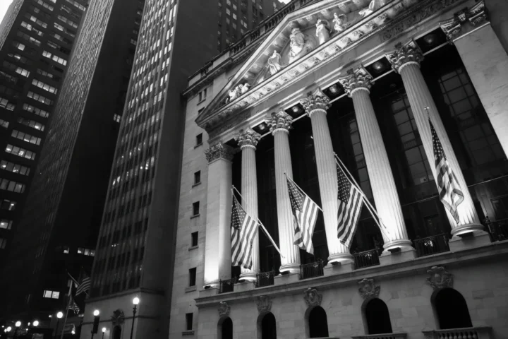 Multiple American flags fluttering in the wind in front of the New York Stock Exchange building on Wall Street